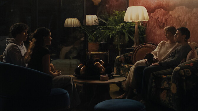 Four people, two men and two women, sit on couches facing each other.