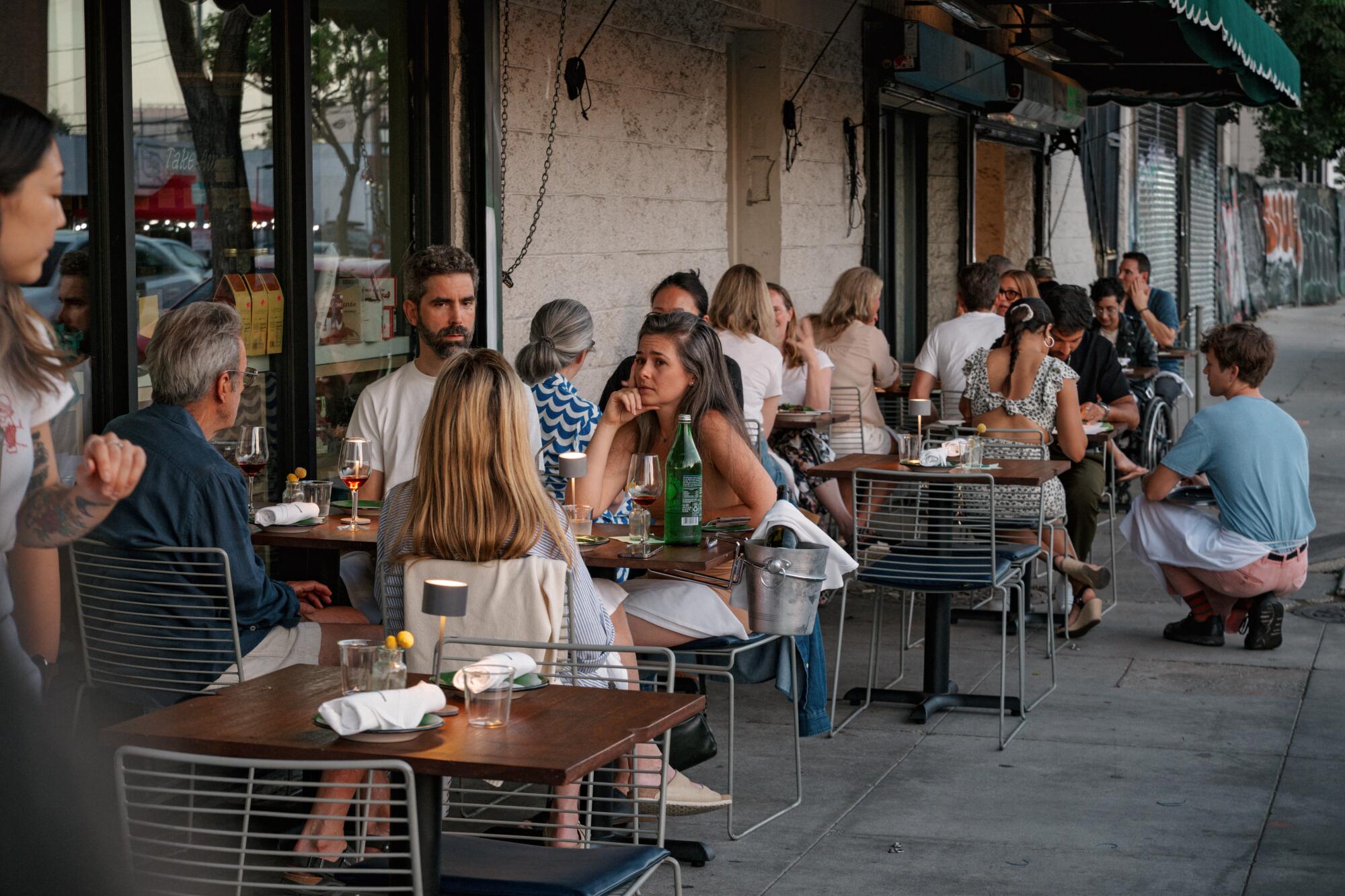Diners fill the sidewalk tables in front of Sqirl on an early summer evening.