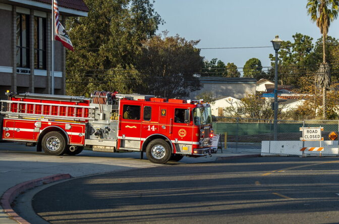A firetruck pulls out of a station into a street.