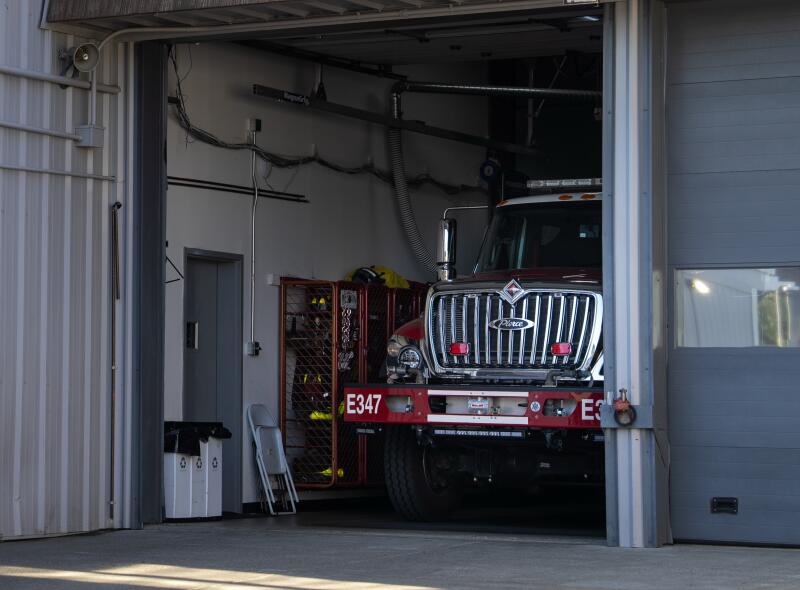 A fire engine parked at a station with its bay door opened