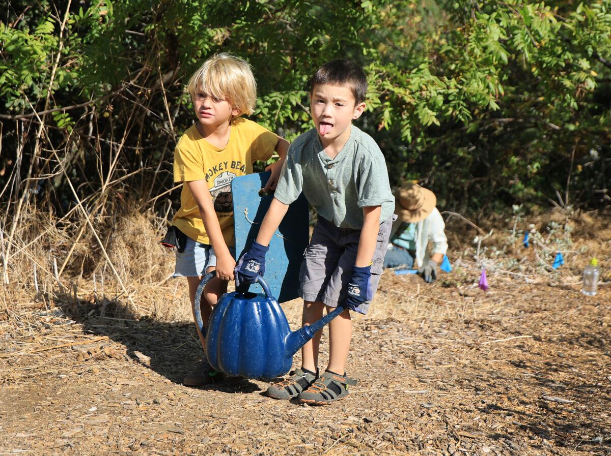 Two 6-year-old boys carry water together