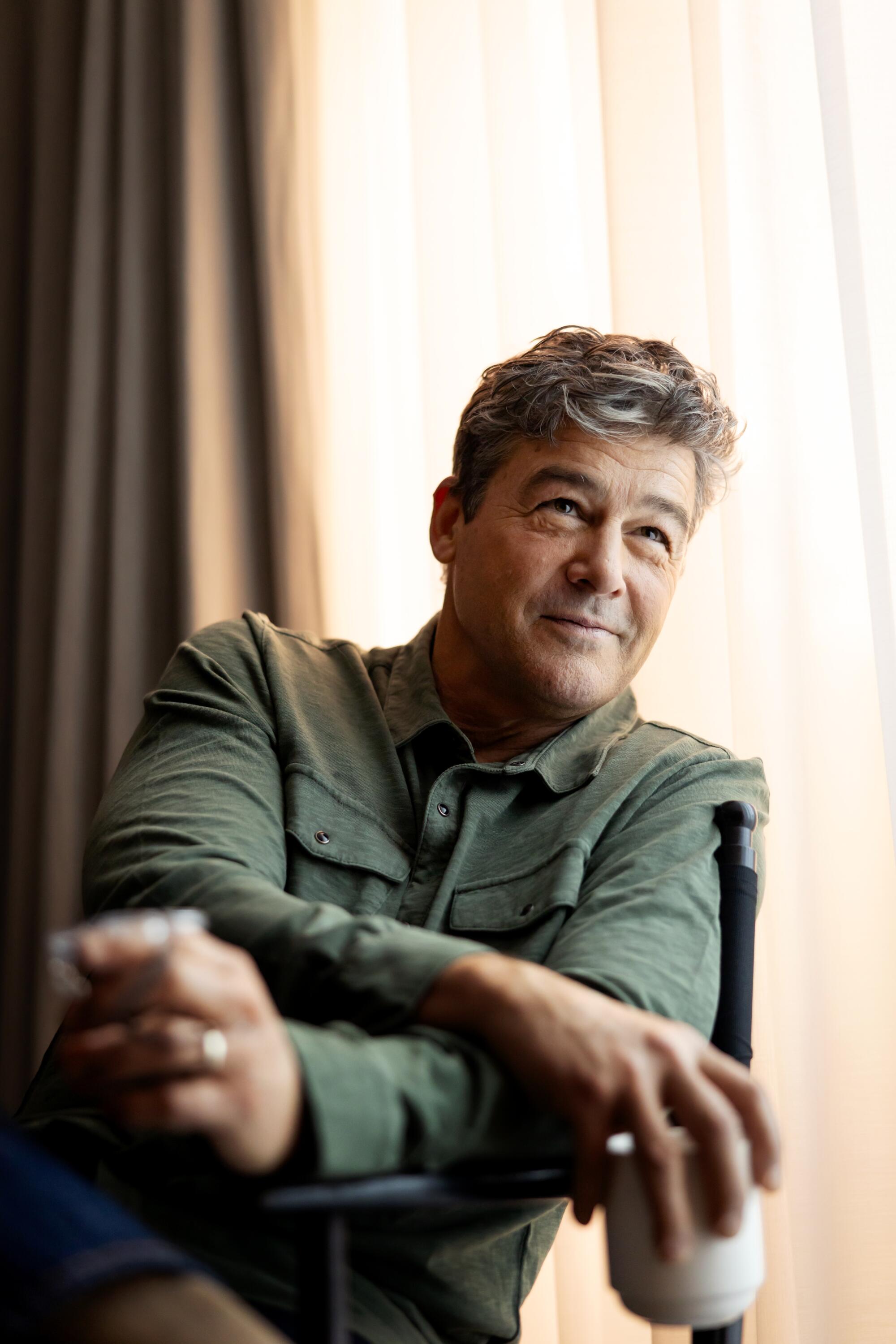 Kyle Chandler in a chair holding a mug