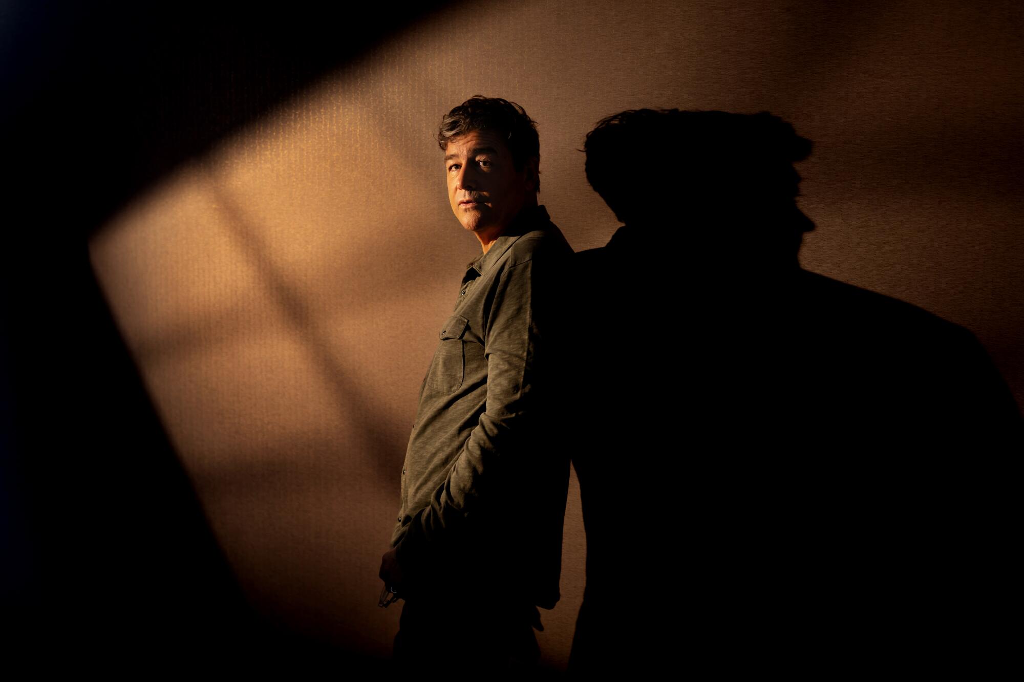 Kyle Chandler posing for a photo against a wall