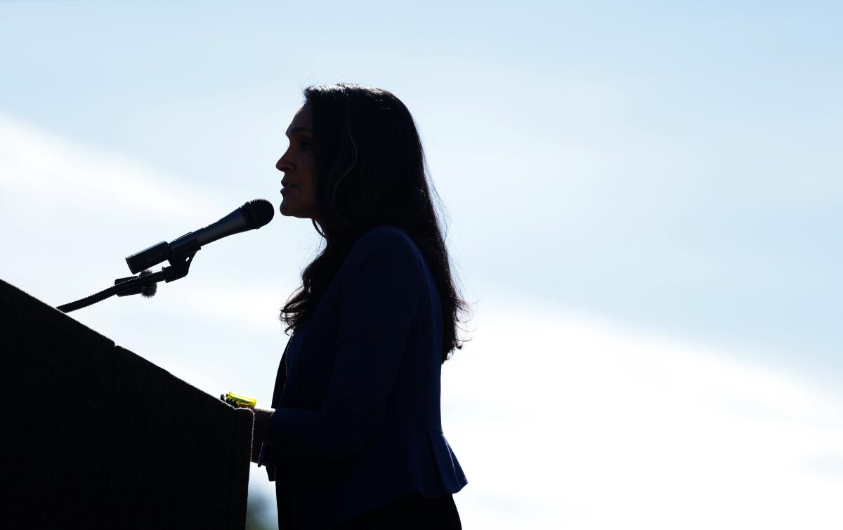 A silhouette of a woman in profile speaking at a podium