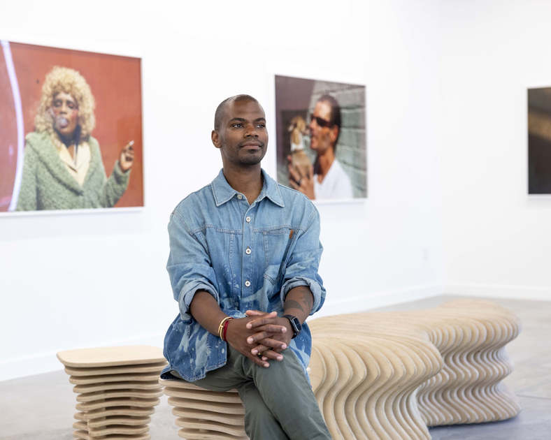 A man stands in front of a gallery wall.