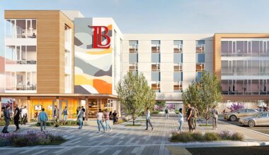A modern building with a colorful mural, surrounded by people and landscaped areas.