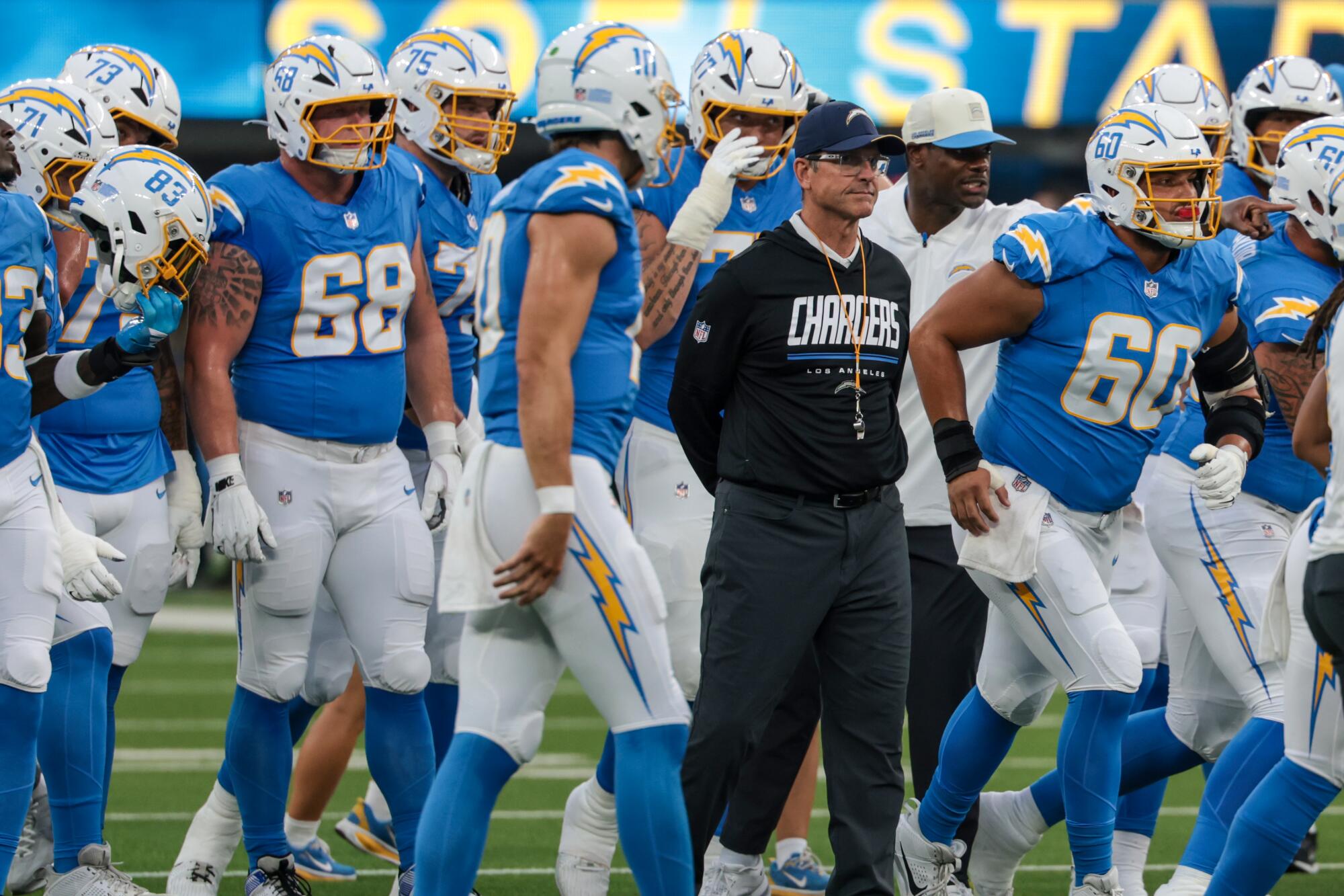 Chargers coach Jim Harbaugh walks on the field with his players during a preseason loss to the 49ers.