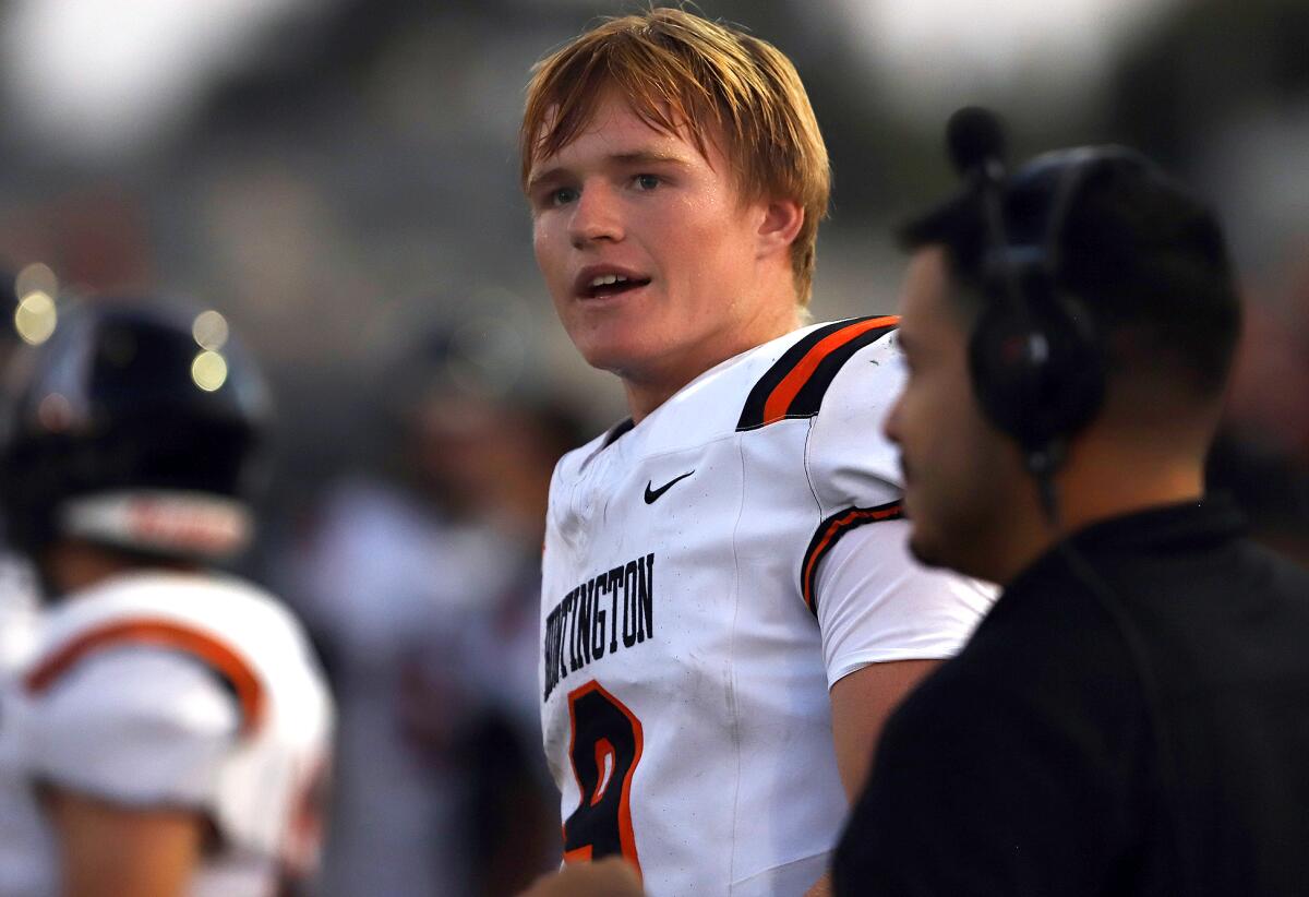 Huntington Beach quarterback Brady Edmunds (9) and his coach watch their defense against Millikan on Thursday.