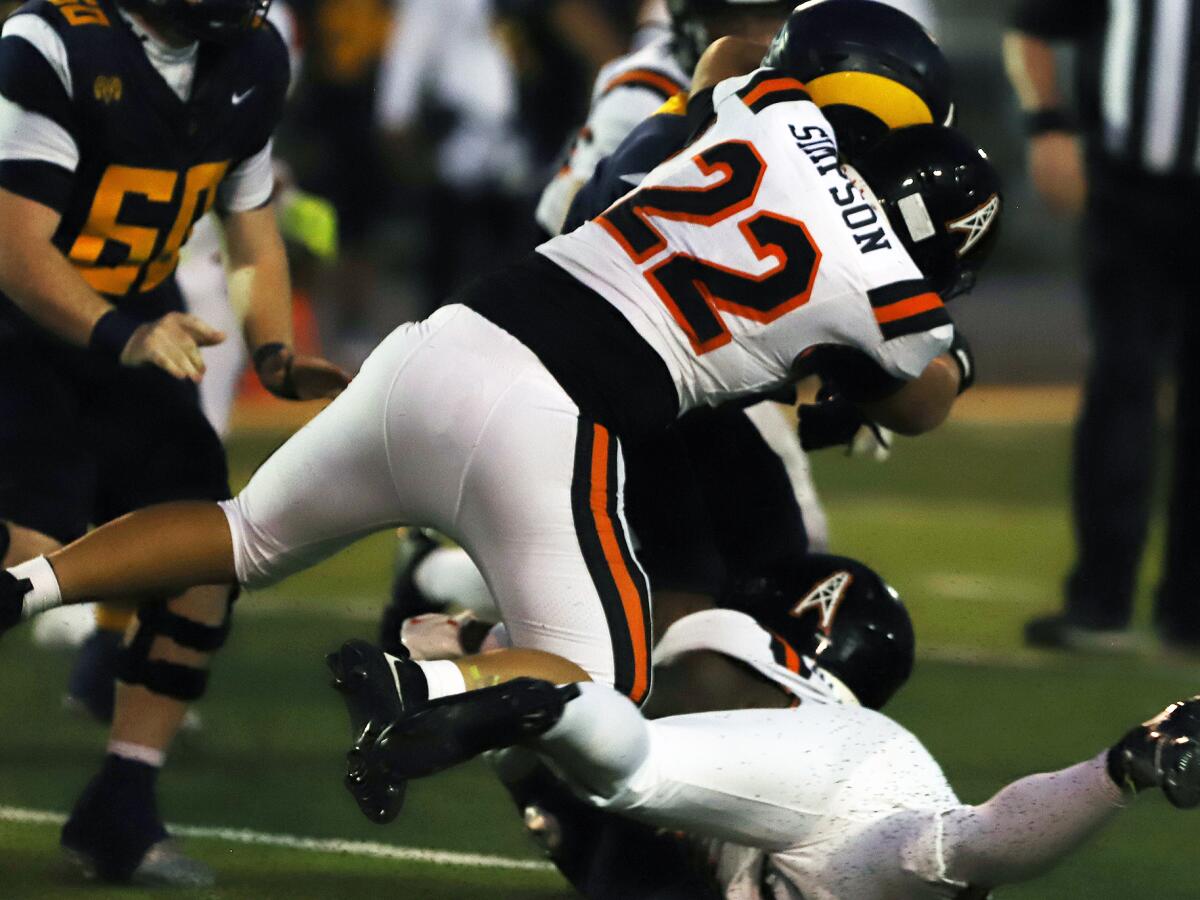Huntington Beach's Jacob Simpson (22) dives to tackle Millikan's Ryan Carter (7) in a nonleague football opener on Thursday.