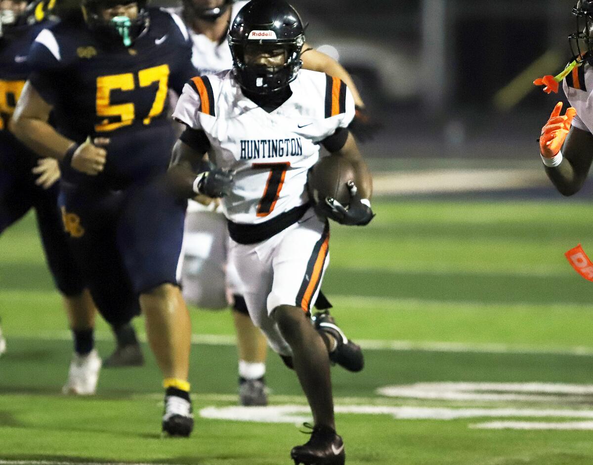 Huntington Beach's Kye Crump (7) runs through the defense after a reception against Millikan on Thursday.