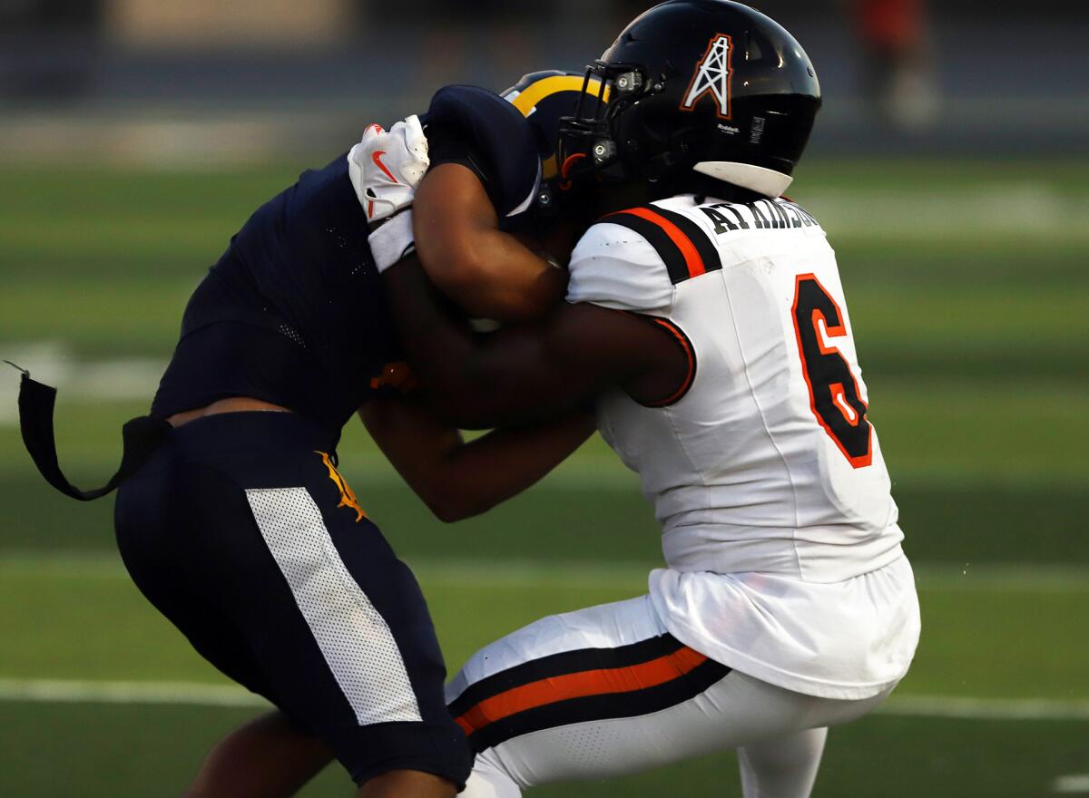 Huntington Beach's Dallas "DJ" Miller (6) tackles Millikan's Ryan Carter (7) in a nonleague football opener on Thursday.