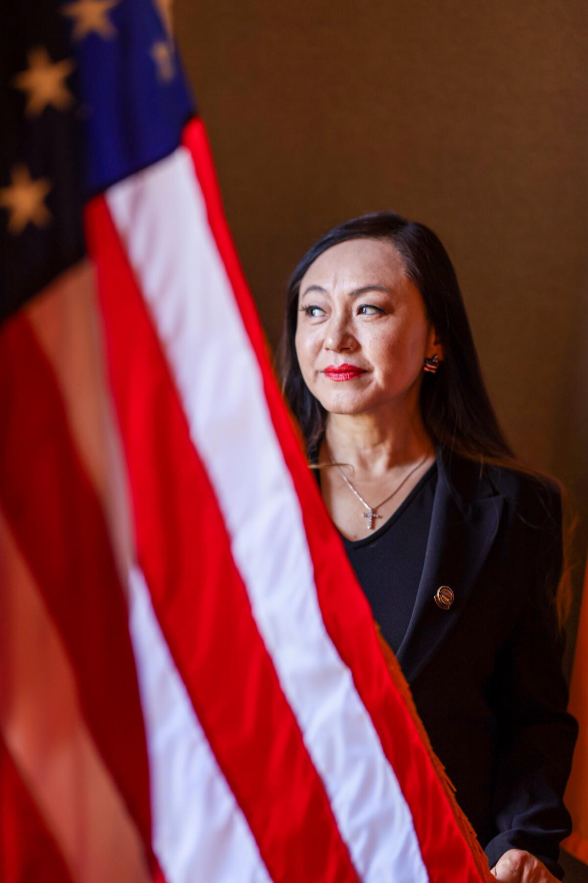 A woman poses with the flag of the United States.