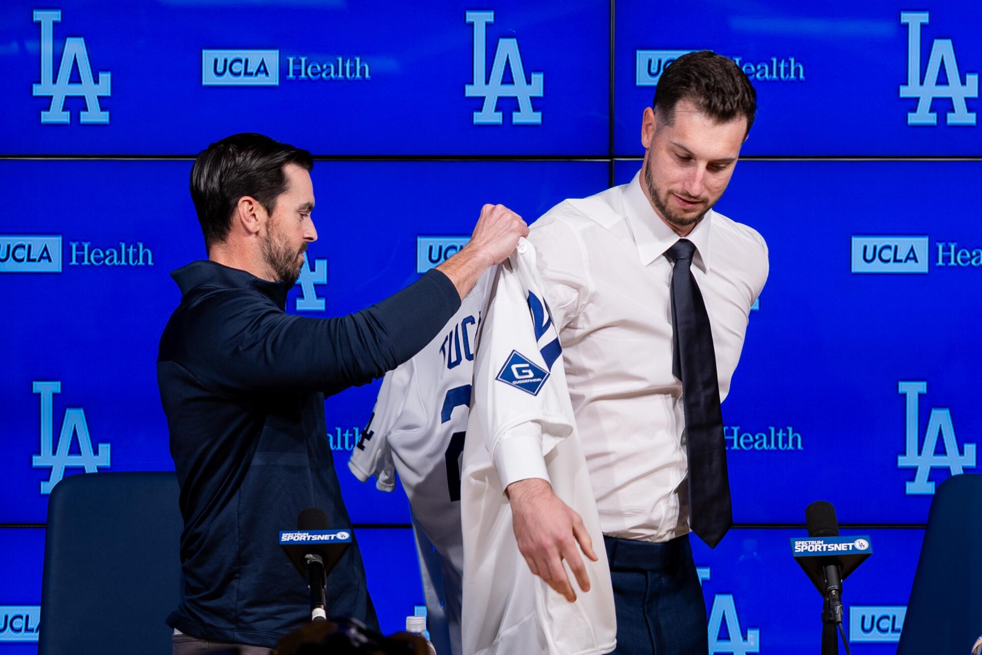 Brandon Gomes, Dodgers executive president and general manager, helps new signee Kyle Tucker put on a Dodgers jersey.