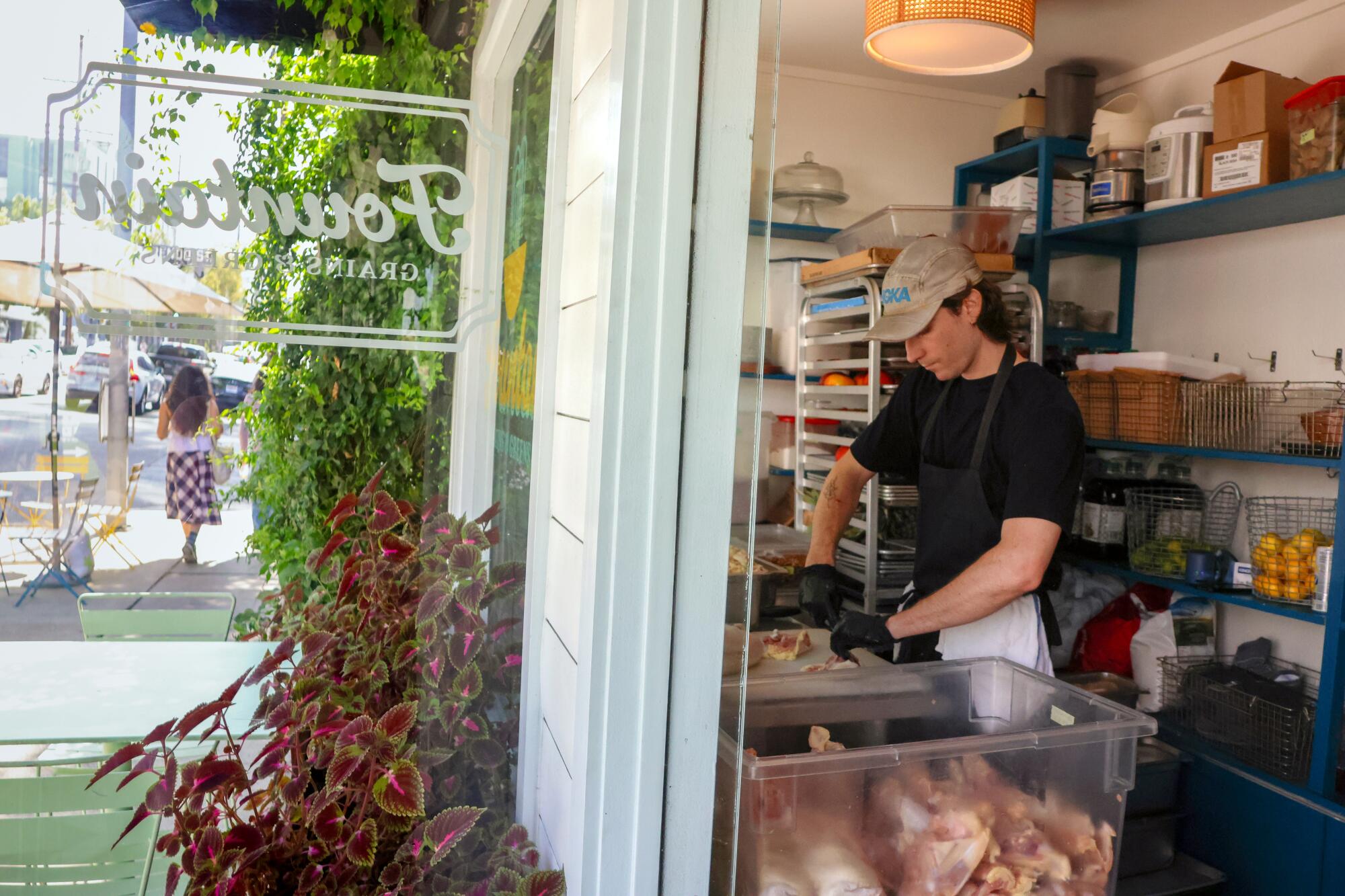 A butcher prepares chicken in a restaurant kitchen