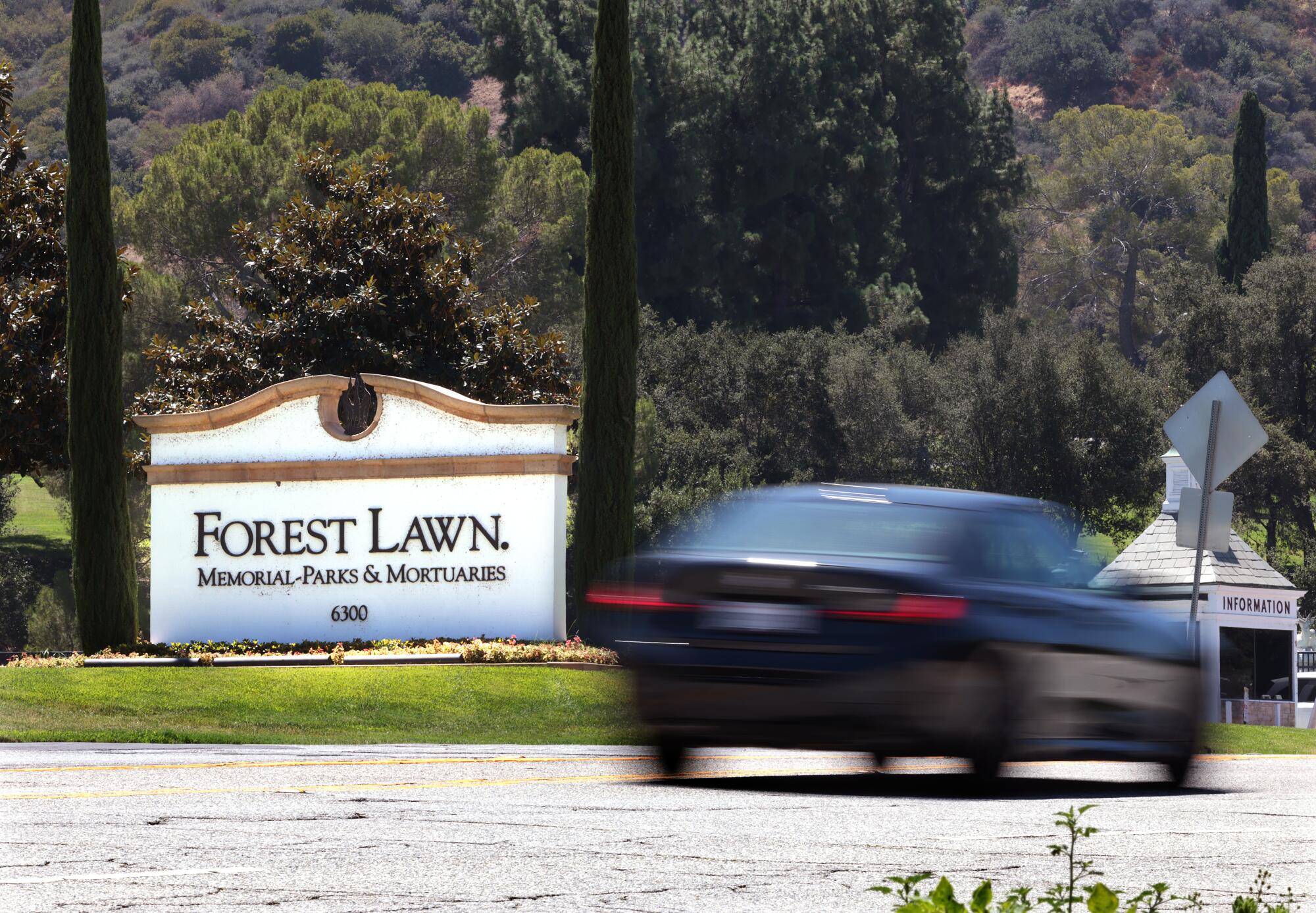 A vehicle passes a sign that says 'Forest Lawn.'