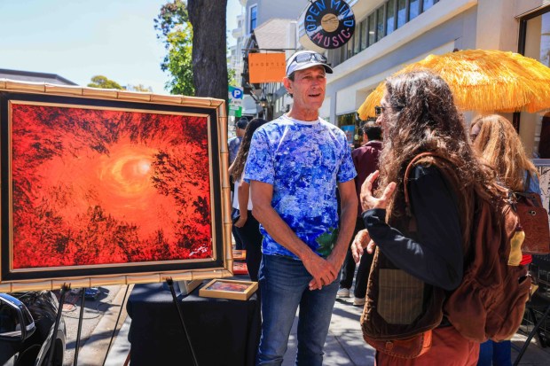 Artist Mike Wilson, left, displays his work for sale as he talks to a person during the Rockridge Rock-N-Stroll event along College Avenue in Oakland, Calif., on Saturday, Aug. 22, 2026. (Ray Chavez/Bay Area News Group)