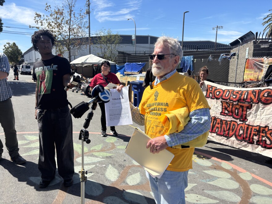 At the press conference, lead Attorney Anthony Prince holds up a notice that was posted at 8th and Harrison earlier that morning saying the encampment will be closed on September 8.