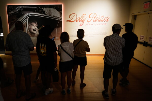 Guests visit the Dolly Parton exhibit at the Country Music Hall of Fame on Tuesday, Aug. 25, 2026, in Nashville. (AP Photo/George Walker IV)