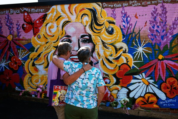 Tracy Ross, left, and Patricia Fonner visit a mural of Dolly Parton on Tuesday, Aug. 25, 2026, in Nashville, Tenn. (AP Photo/George Walker IV)
