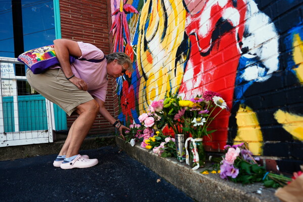 Tracy Ross leaves flowers at a mural of Dolly Parton on Tuesday, Aug. 25, 2026, in Nashville, Tenn. (AP Photo/George Walker IV)