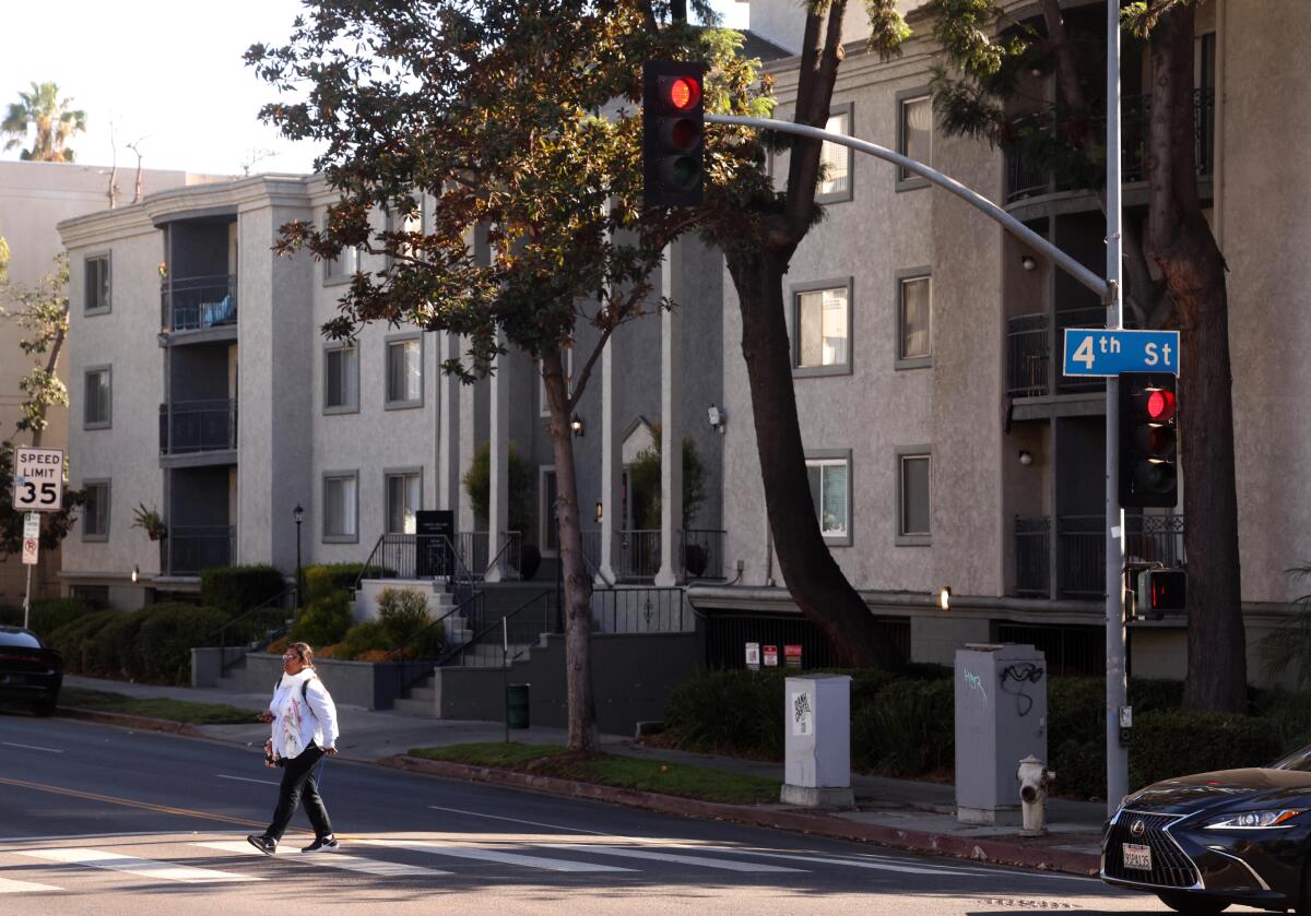 A pedestrian walks past the Virgil Square Apartments.