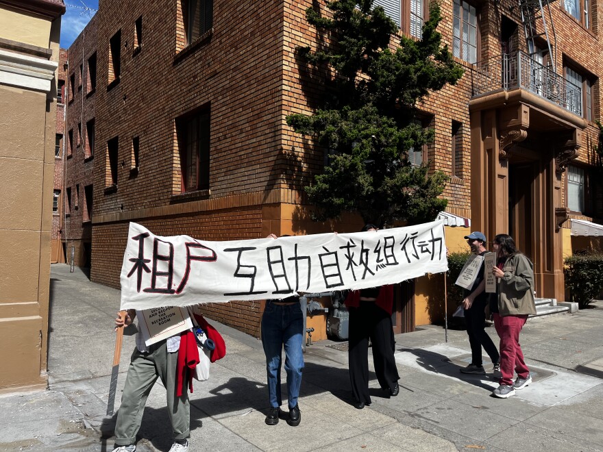 TANC organizers holding a banner reading "The Tenant Mutual Aid Committee Is In Caption"