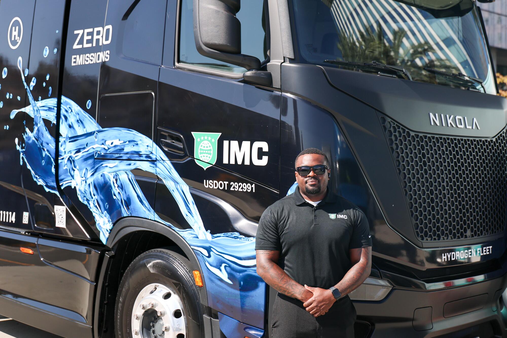 A man stands beside a Nikola hydrogen-electric Class 8 semi-truck.