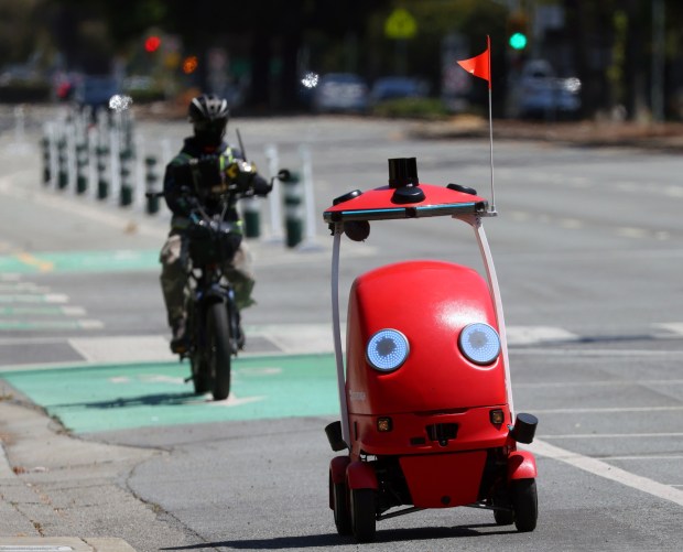 An autonomous delivery robot from DoorDash moves along Fremont Boulevard while followed bay a human supervisor riding a bicycle on Wednesday, Aug. 12, 2026, in Fremont, Calif. (Aric Crabb/Bay Area News Group)