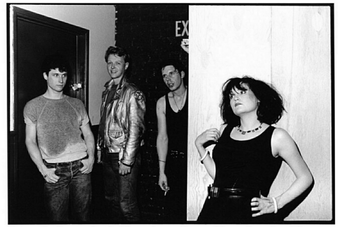 A black and white photo of four people at the backstage of a venue.