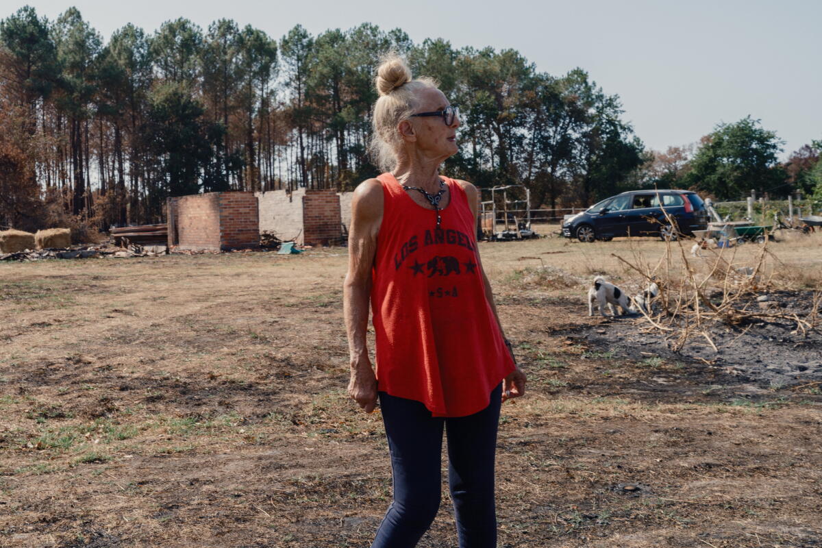 a woman surveys her property that burned in a fire