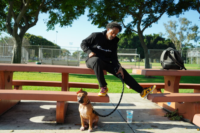 A man sits on a park bench with his dog.