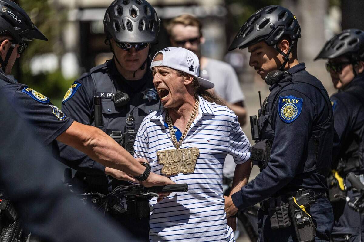 A man is detained by Sacramento police officers after he allegedly pepper-sprayed people protesting against conservative influencer Nick Shirley at the state Capitol on Wednesday.