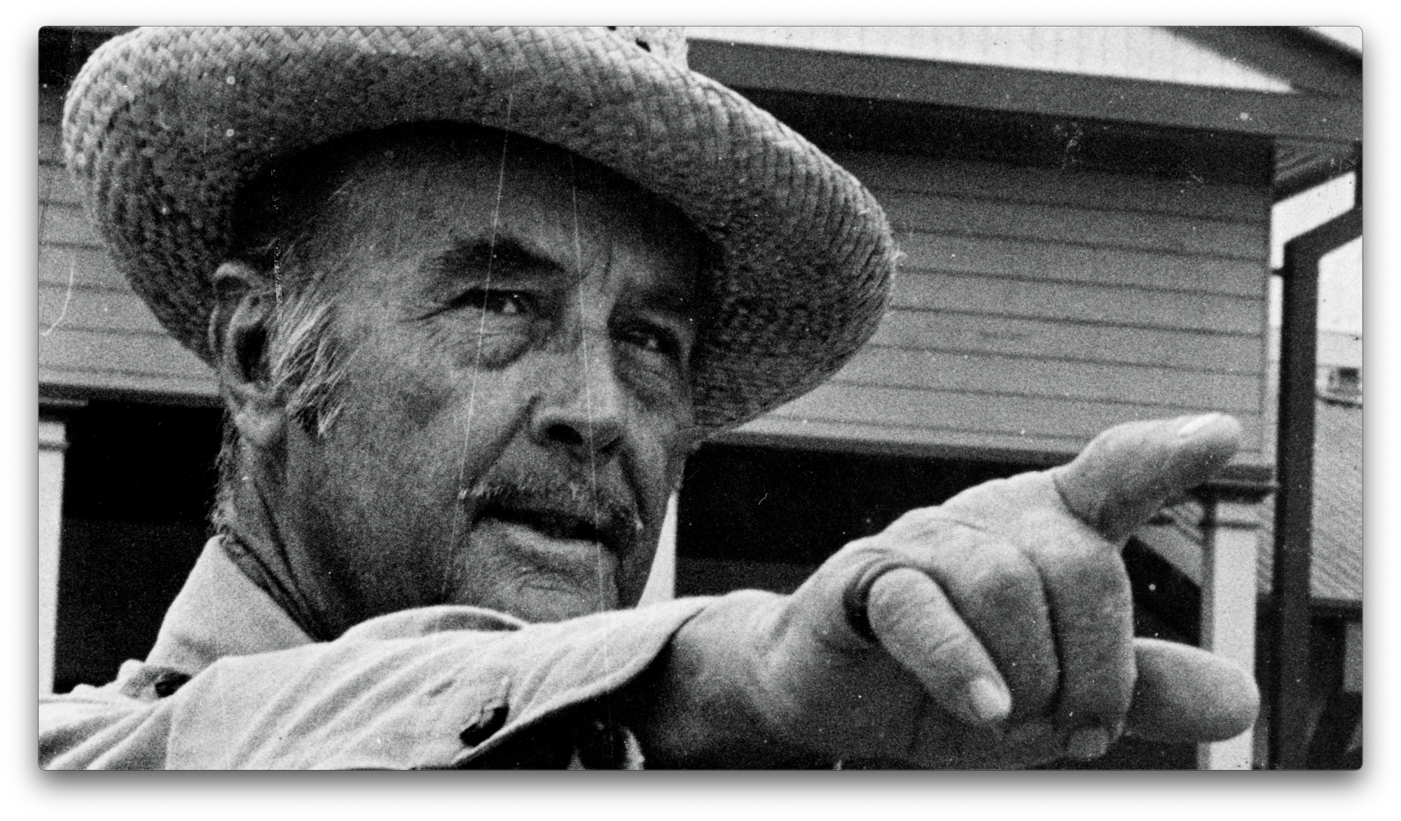 A mustached man in a a straw-like hat.