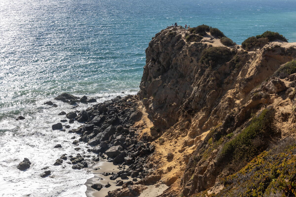 a cliff rises above the ocean