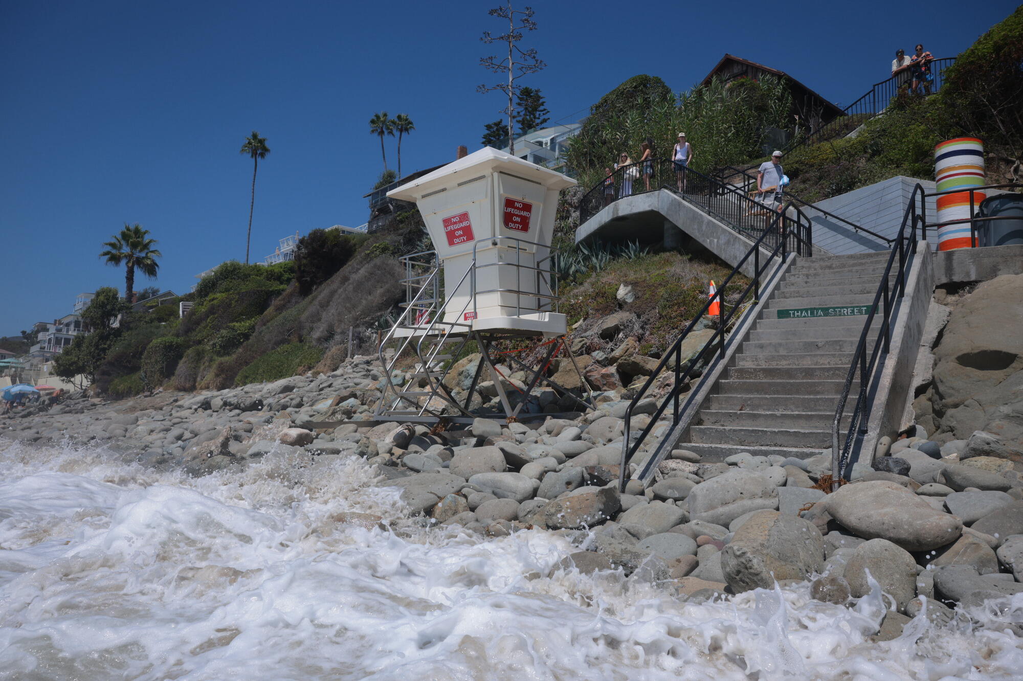People walk down a set of stairs past a lifeguard tower
