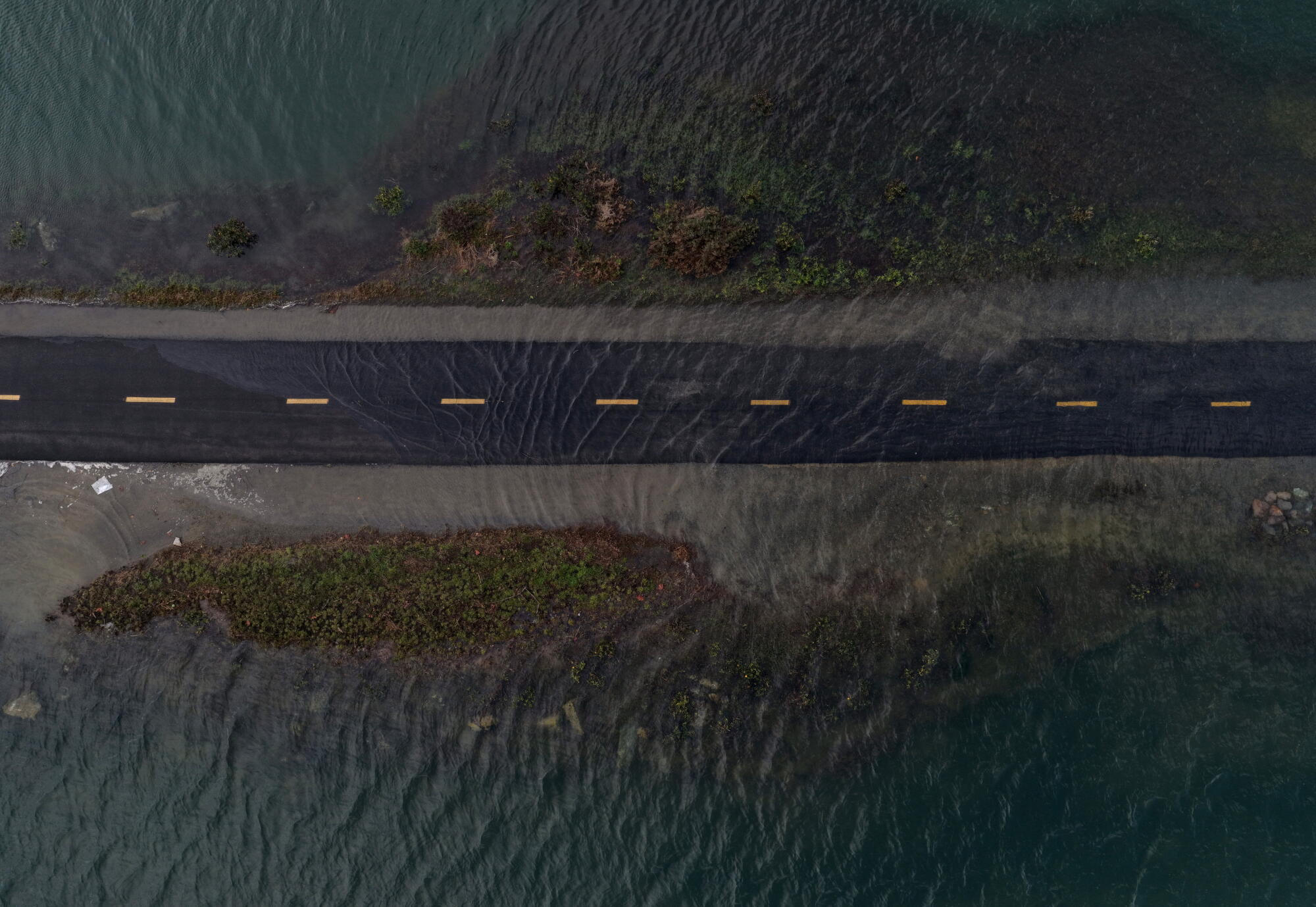 an aerial view, seawater floods a bike path