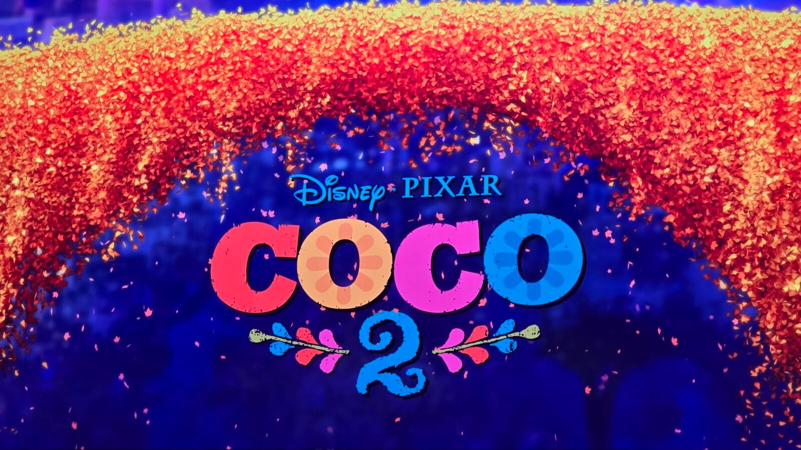 Colorful confetti arch over a blue backdrop with the words DisneyPixar Coco in vibrant letters suggesting a Coco promotion or premiere
