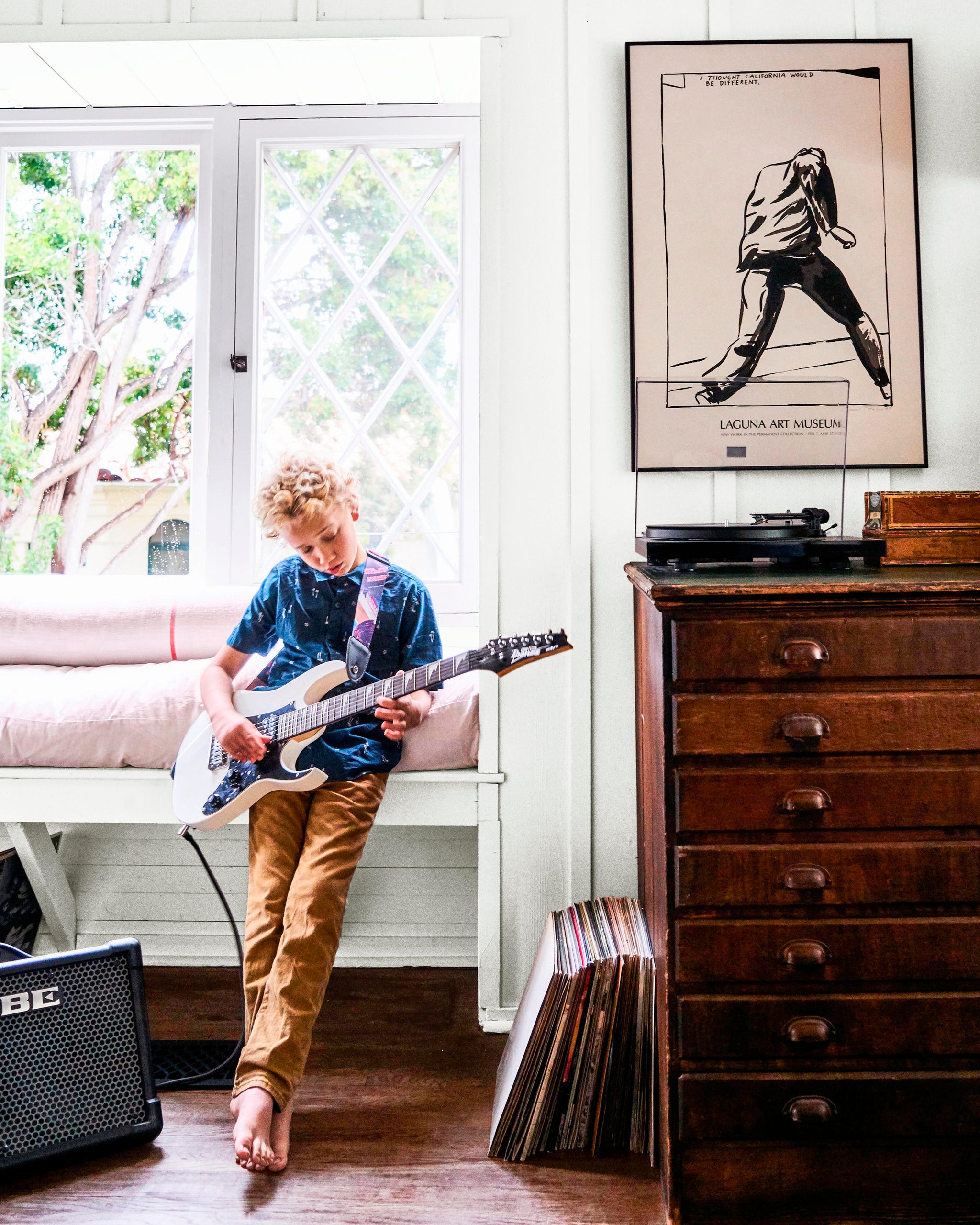 living room area with a wood dresser and a boy playing guitar living room area with a wood dresser and a boy playing guitar