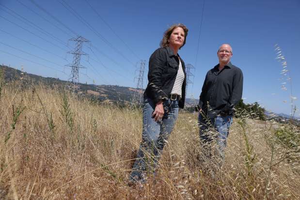 Natalie Manning and Will Abrams are part of the Utility Wildfire Survivor Coalition. Photo taken along Skyfarm Drive at the site of a burned lot under power lines in Santa Rosa on Monday, June 16, 2025. (Christopher Chung / The Press Democrat)