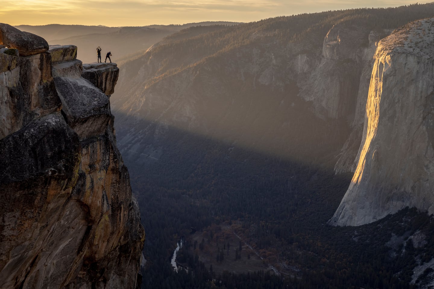 Visitors pose for a photograph on a ledge near Taft Point in Yosemite National Park.