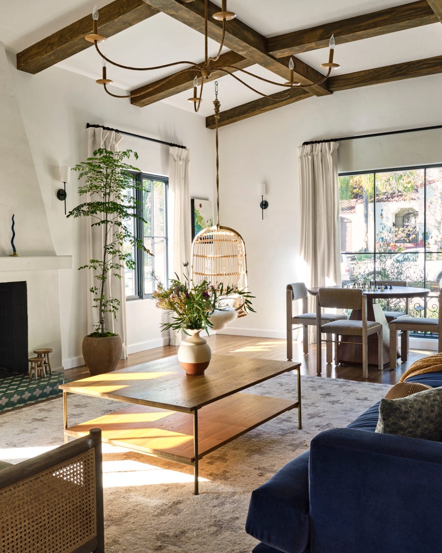 a bright and airy living room characterized by high ceilings with exposed wooden beams