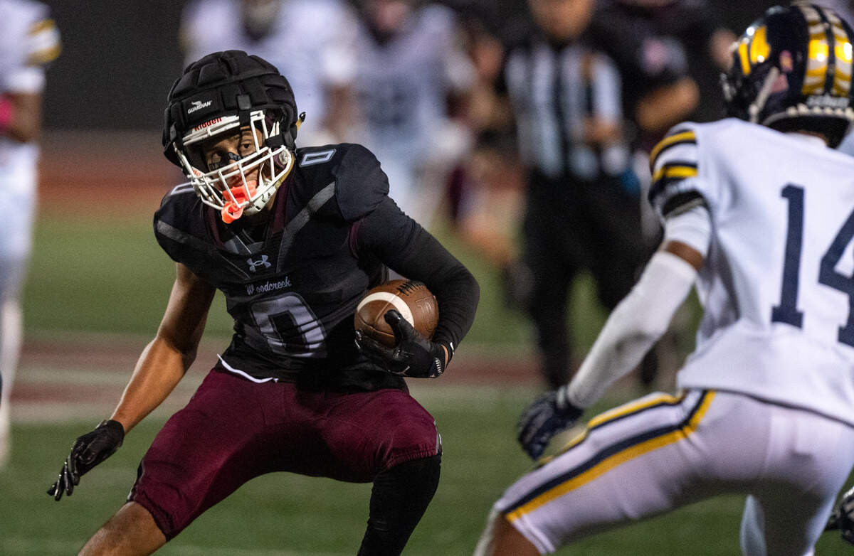The Woodcreek Timberwolves' Trace Murchison looks to evade the Inderkum Tigers’ Jayden Corry as he picks up first down yardage on a reception in the fourth quarter on Friday, Oct. 17, in Roseville.
