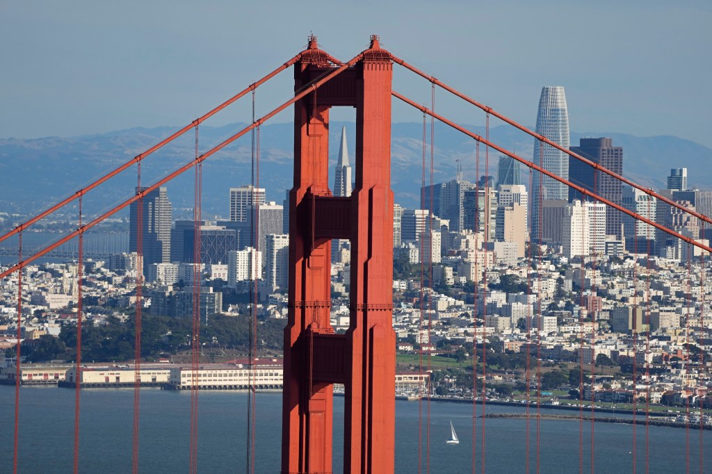 The Golden Gate Bridge in the foreground with the San Francisco skyline and hills in the background.