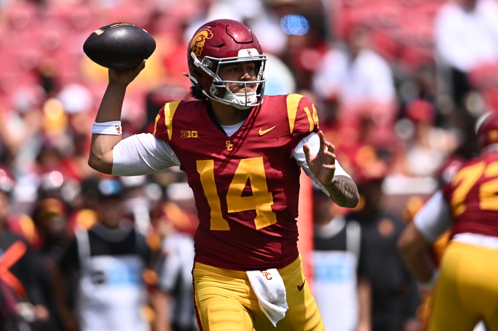 Football player Jayden Maiava, in a red and gold uniform, holds a football up to throw it.