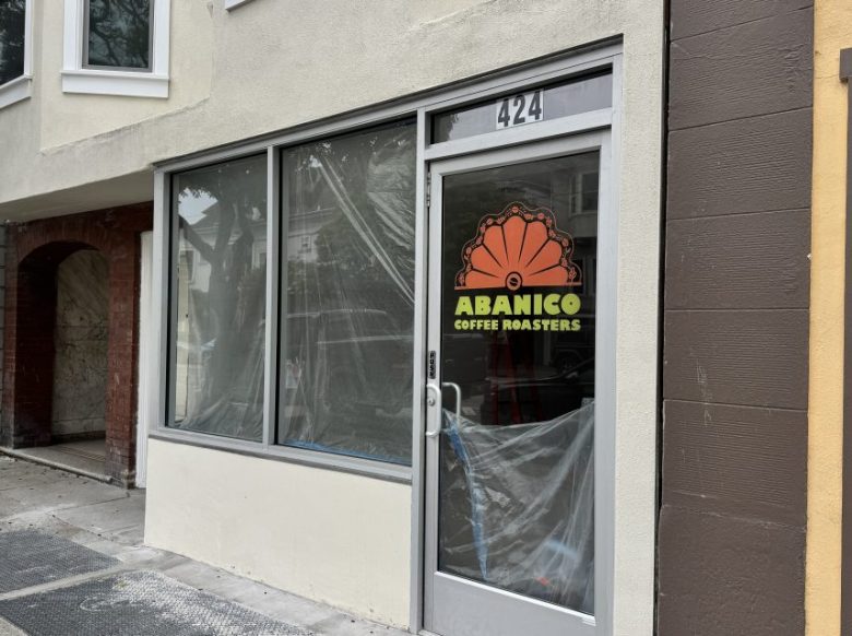 Street view of a storefront with large windows, a glass door displaying “Abanico Coffee Roasters,” and plastic covering the interior. The address number 424 is above the door.