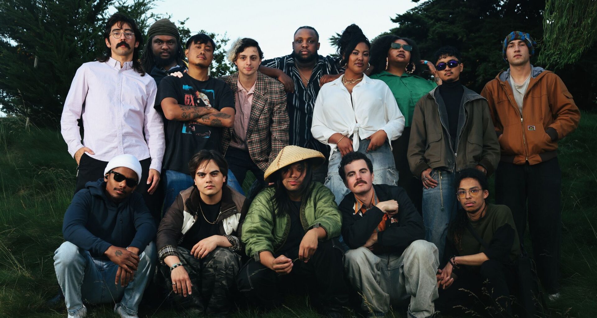 big group of musicians stand and crouch, slightly smiling