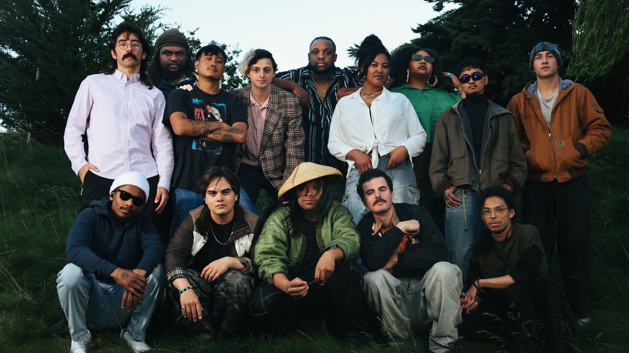big group of musicians stand and crouch, slightly smiling