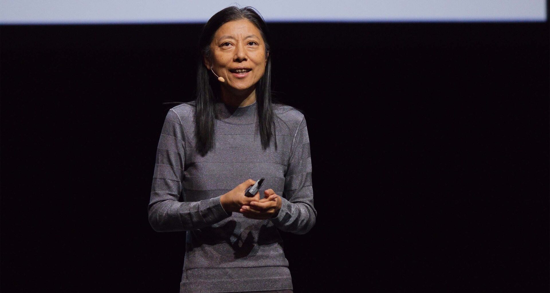 Dawn Song stands on a stage speaking into a headset microphone.