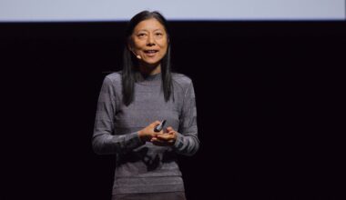 Dawn Song stands on a stage speaking into a headset microphone.