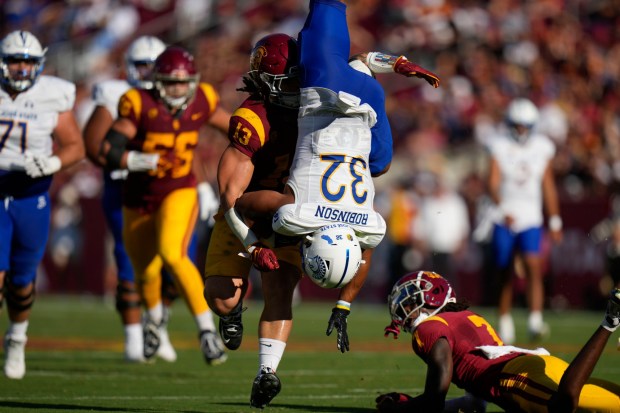 San Jose State running back Kairee Robinson (32) is grabbed by Southern California linebacker Mason Cobb (13) after he jumped over USC safety Calen Bullock (7) during the first half of an NCAA college football game in Los Angeles, Saturday, Aug. 26, 2023. (AP Photo/Jae C. Hong)
